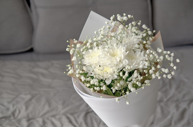 Bouquet of white chrysanthemums and gypsophila wrapped in craft paper delicate bouquet of white flowers Spring bouquet of white chrysanthemums closeup