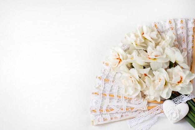 a bouquet of white daffodils, lace fan and heart