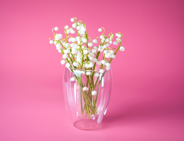 Foto bouquet di fiori bianchi in un vaso di vetro su uno sfondo rosa