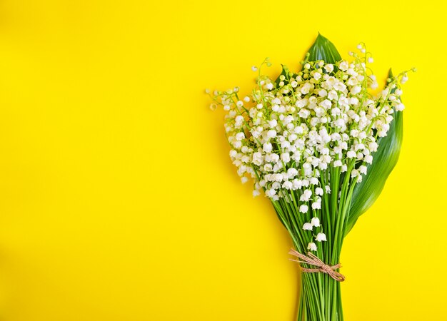 Bouquet of white lilies of the valley on a yellow background