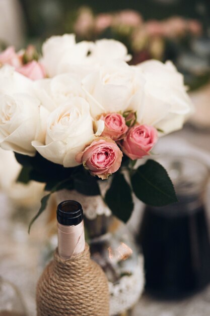 Bouquet of white peonies and pink roses stands on the dinner table