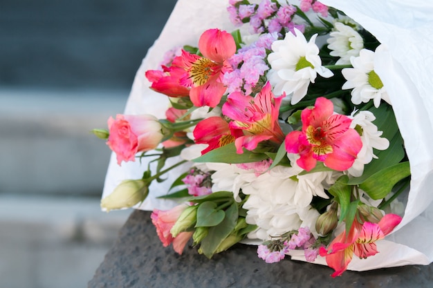 A bouquet of white and pink flowers in a paper wrapper.