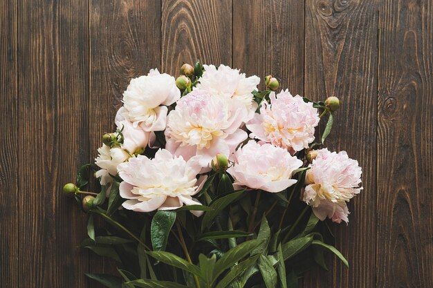 Foto bouquet di fiori di peonie rosa bianche su uno sfondo di legno