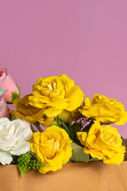 bouquet of white pink and yellow roses in a paper box on a pink background