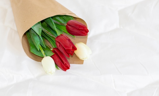 bouquet of white and red color tulips on white blanket on the bed celebrate a holiday valentine's