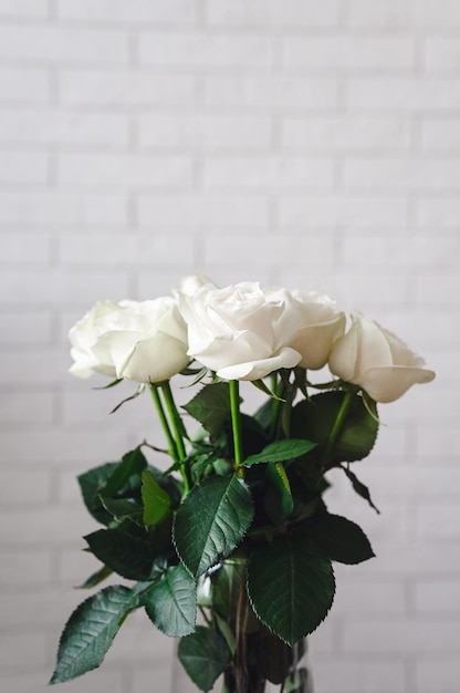 Bouquet of white roses on brick wall background copy space