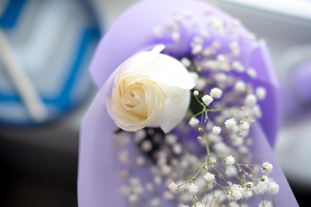 Bouquet of white roses in purple packaging on the windowsill top view