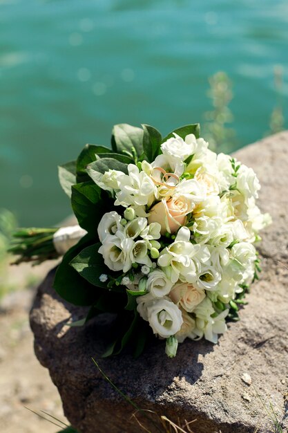 A bouquet of white roses on the stone bank of the river