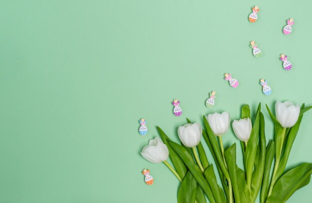 Bouquet of white tulips and decorative clothespins on a green background, copy space, flat lay