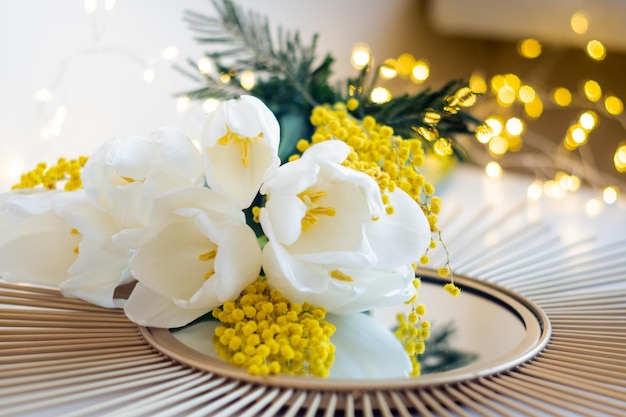 Bouquet of white tulips and mimosa flowers on mirror tray