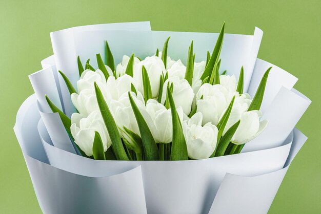 Foto un bouquet di tulipani bianchi su uno sfondo verde pastello fiori in fiore concetto festivo