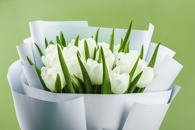 Foto un bouquet di tulipani bianchi su uno sfondo verde pastello fiori in fiore concetto festivo