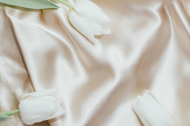 Bouquet of white tulips on silk golden nude satin background