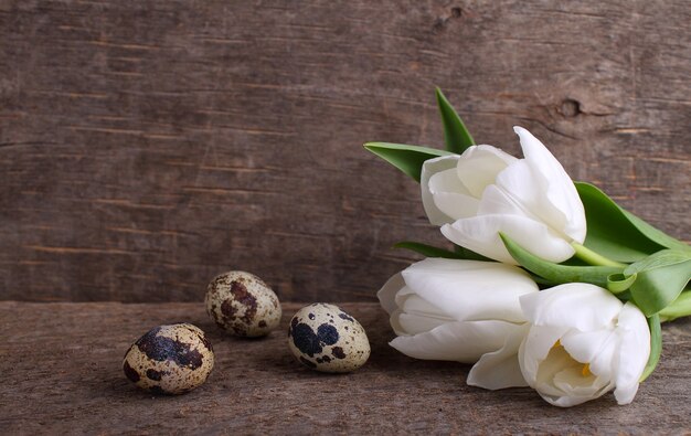 Bouquet of white tulips in a white jug on an old wooden background.