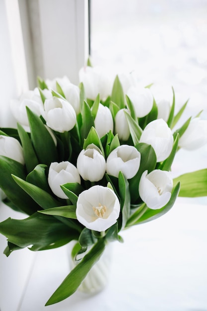 A bouquet of white tulips with green leaves