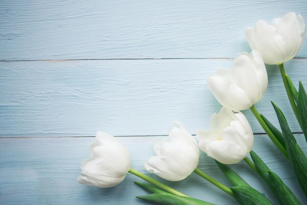 Bouquet of white tulips on wooden background Flat lay top view copy space Easter or Mothers Day greeting card