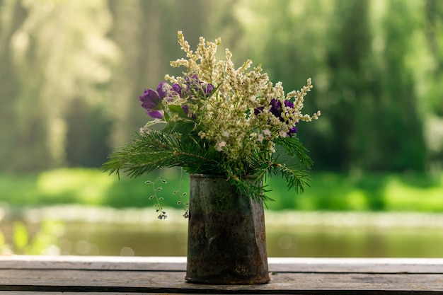 ぼやけた自然の背景にさびたブリキ缶の野生の野原植物の花束