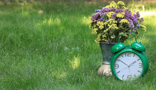 bouquet of wild flowers and an alarm clock on the grass