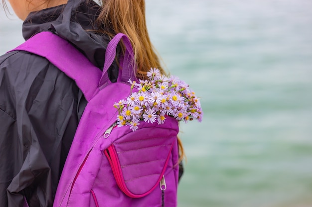 A bouquet of wild flowers in a sports backpack of a girl