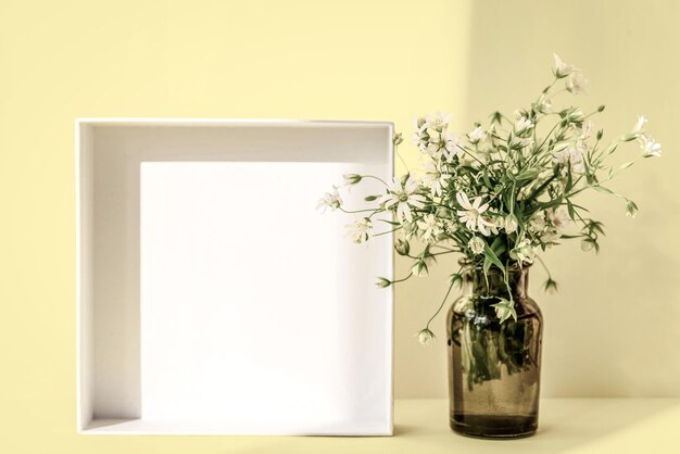 Bouquet of wild flowers in vase on pastel yellow background