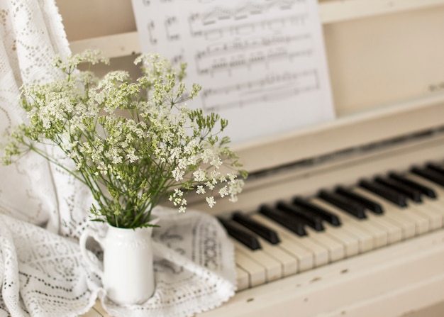 Fiori selvatici del mazzo sul piano bianco con le note. foto retrò