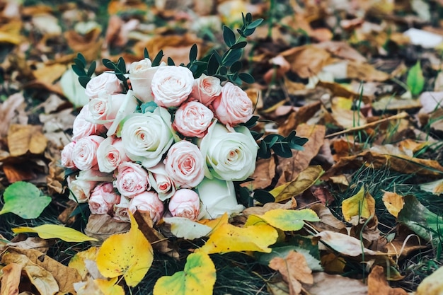 Bouquet with pink and white roses on a background of autumn leaves