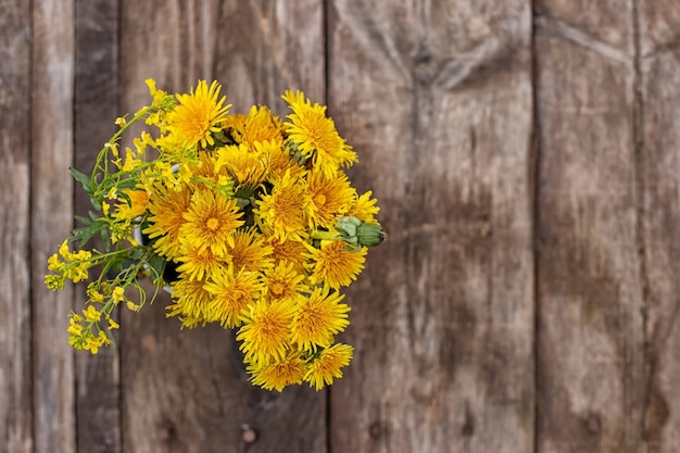 木製の背景に黄色のタンポポの花束