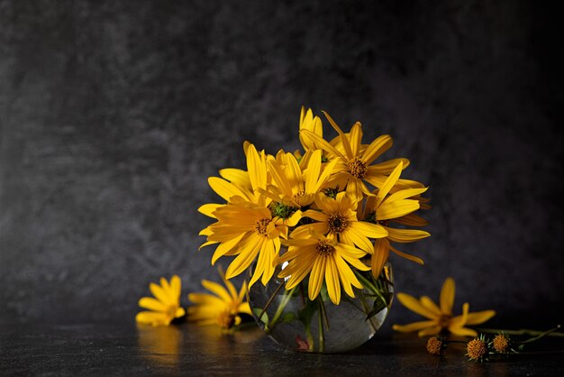 Foto bouquet di fiori gialli su uno sfondo scuro in stile grunge astratto arrangiamento floreale della madre