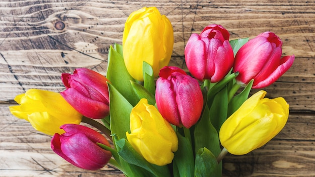 Bouquet of yellow and pink tulips on a wooden .