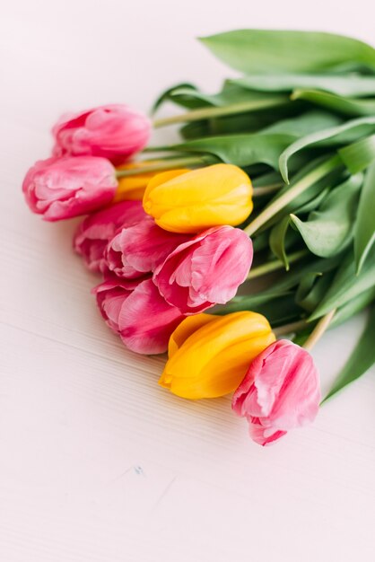 Bouquet yellow and rose tulip  on  vintage chair in white room