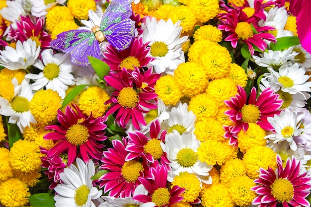 a bouquet of yellow roses and white flowers and purple butterfly