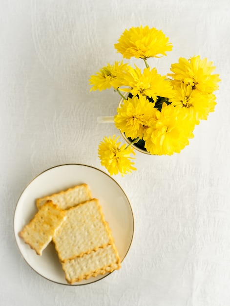 Bouquet of yellow spring flowers and biscuits on plate