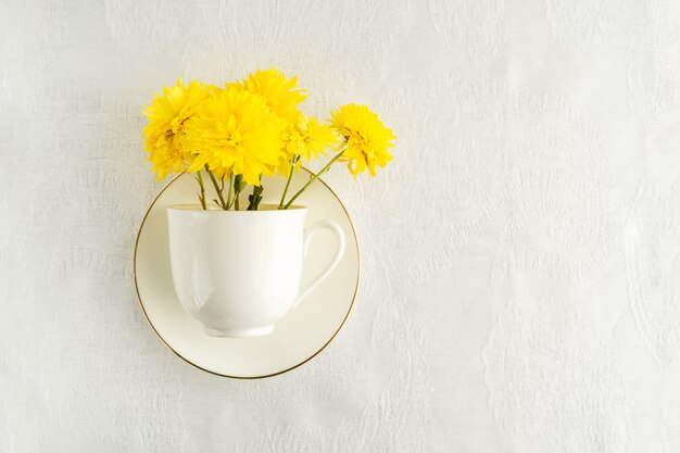 Bouquet of yellow spring flowers in white tea cup