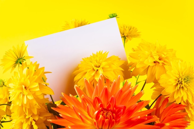 Bouquet of yellow summer flowers and blank greeting card on bright background