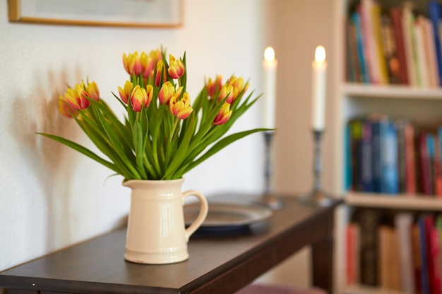 Bouquet of yellow tulips in a vase as a living room decoration or centrepiece symbolising love affection or caring gesture Bunch of freshly cut flowers on a wooden table in a home library or study