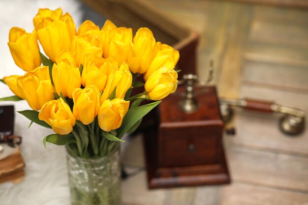 A bouquet of yellow tulips in a vase in the interior of a retro room retro interior with bouquet of tulips old phone and suitcase