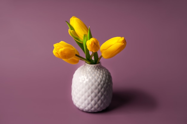 A bouquet of yellow tulips in a vase. Minimalism on a pastel background