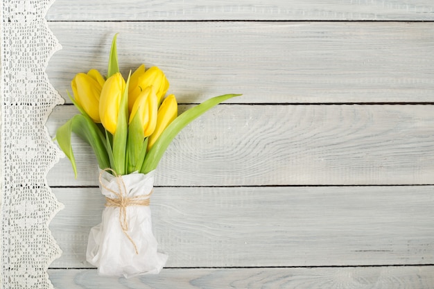 Bouquet of yellow tulips on a white wooden table