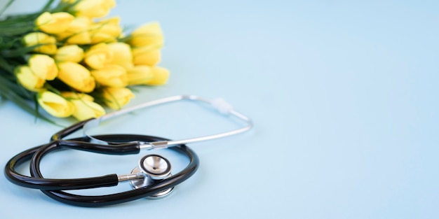 Bouquet of yellow tulips with a stethoscope on a blue