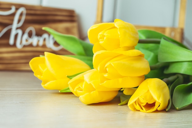 木製の表面に黄色いチューリップの花束。