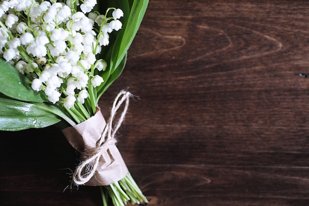 Bouquet of young lilies of the valley on a wooden table