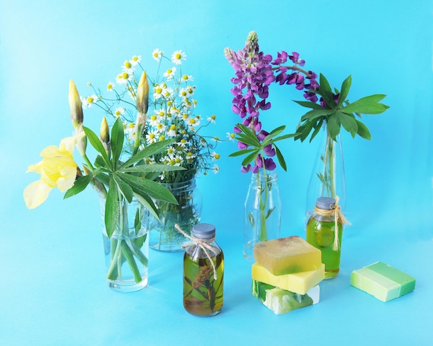 Bouquets of fresh flowers of purple lupine yellow irises and chamomile in transparent glass vases