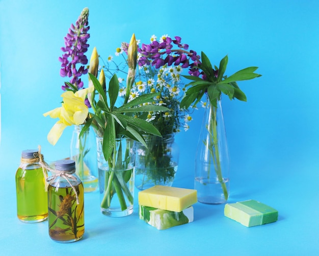 Bouquets of fresh flowers of purple lupine yellow irises and chamomile in transparent glass vases