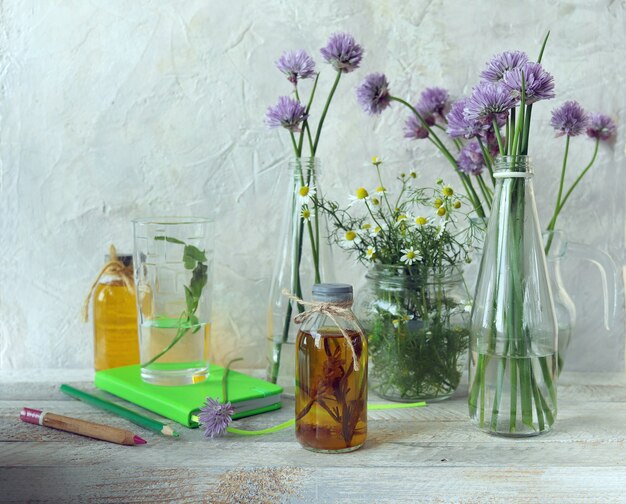 Photo bouquets and tinctures of medicinal herbs in glass containers on a wooden table