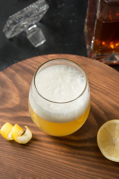 bourbon with lemon juice, sugar syrup and egg white mixed in glass