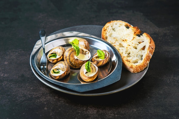 Bourgogne escargot slakken met knoflook kruiden botersaus en brood in aluminium pan op donkere achtergrond