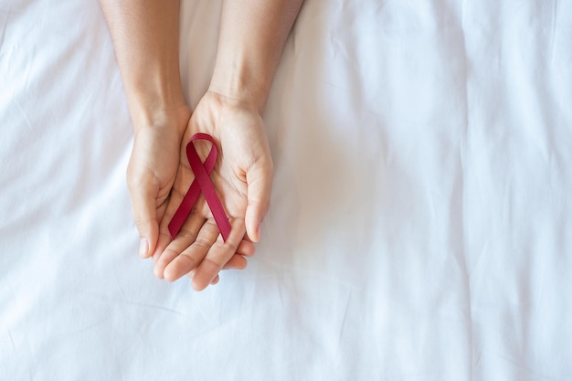 Bourgondië Red Ribbon voor het ondersteunen van mensen die leven en ziekte. Gezondheidszorg en veilige seks concept. December Wereld Aids Dag en Multipel Myeloom Cancer Awareness Month