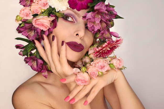 Bourgondische roze manicure en make-up op een vrouw met een verscheidenheid aan bloemen