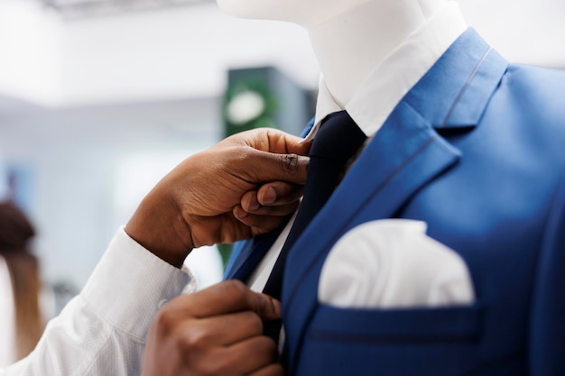 Boutique stylist fixing tie creating formal look on mannequin