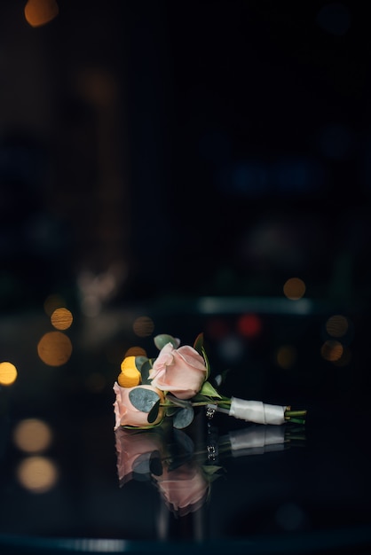 Boutonniere for the groom of delicate pink flowers on a dark blurred background